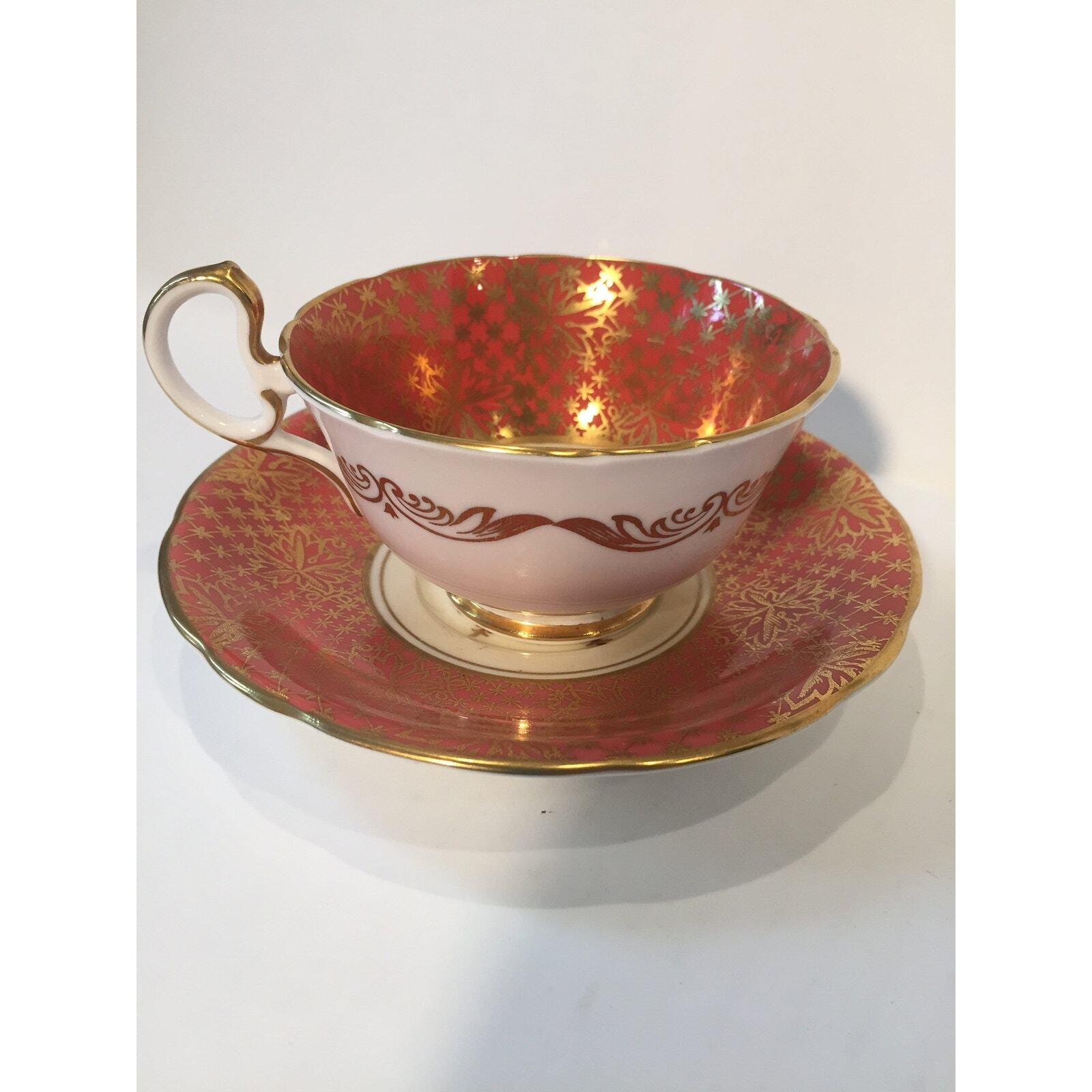 Aynsley teacup and saucer in tropical gilt pattern over dark salmon color Aynsley teacup and saucer in tropical gilt pattern over dark salmon color