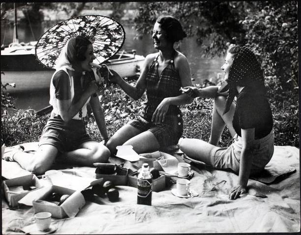 Three young women enjoy feeding each other bananas at a picnic - 1937 Old Photo