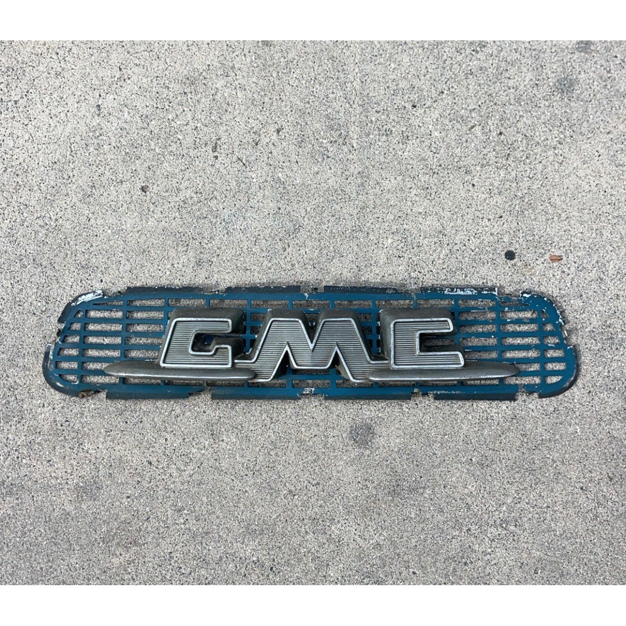 vintage 1955-1956 GMC Truck hood emblem with its original grille insert panel