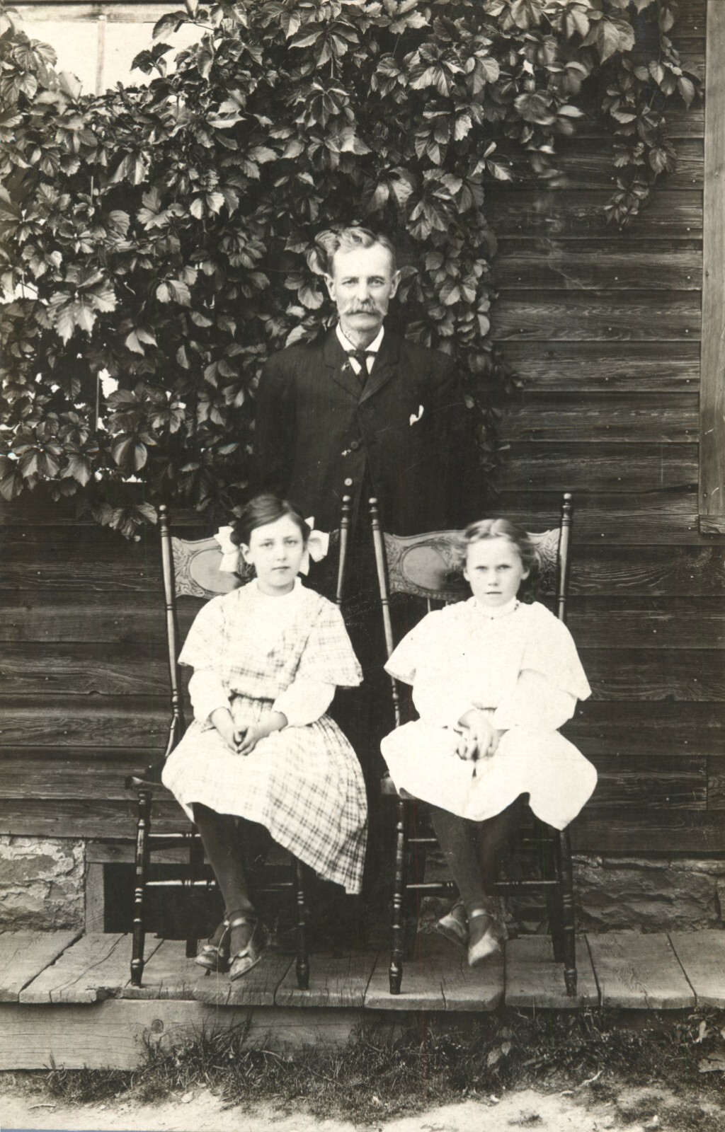 Vtg 1900\'s RPPC Father Posing With Two Daughters Sitting In Chair Outside