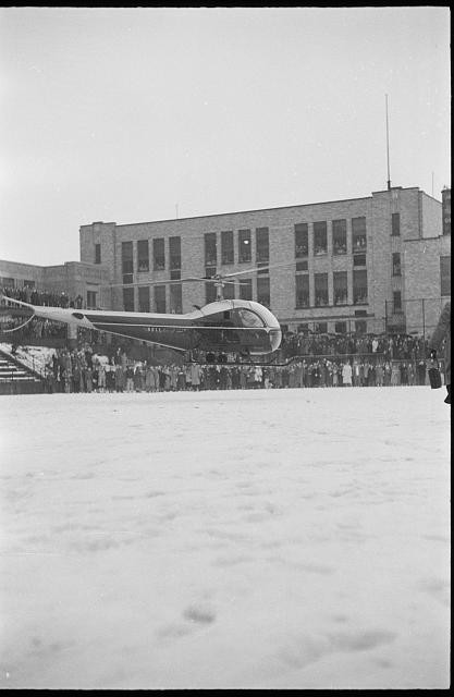 Photo:Homecoming Helicopter Snow Crowd School Building 1950s
