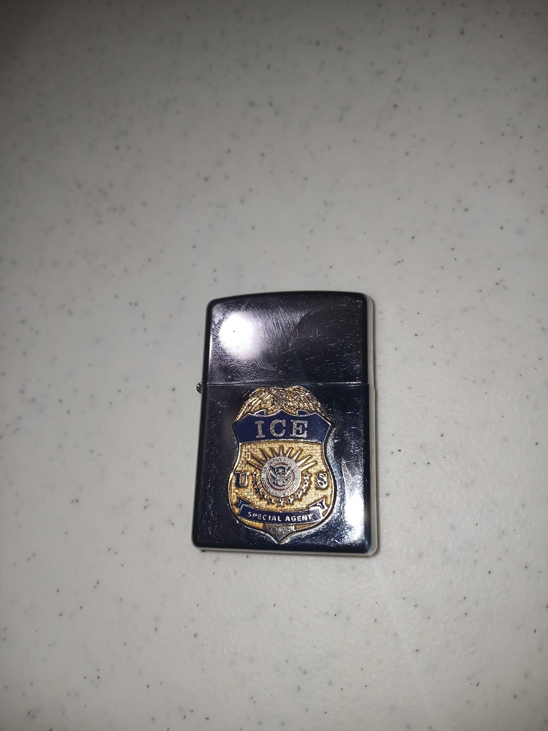 Zippo lighter featuring a gold and blue U.S. Immigration and Customs Enforcement Zippo lighter featuring a gold and blue U.S. Immigration and Customs Enforcement