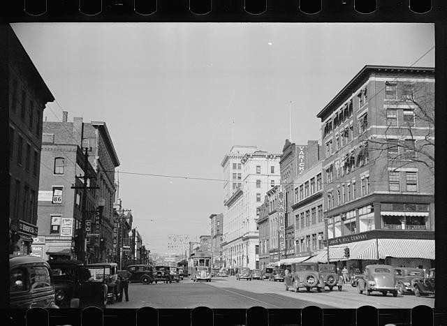 Downtown street scene 1930s cars trolley storefronts municipal building