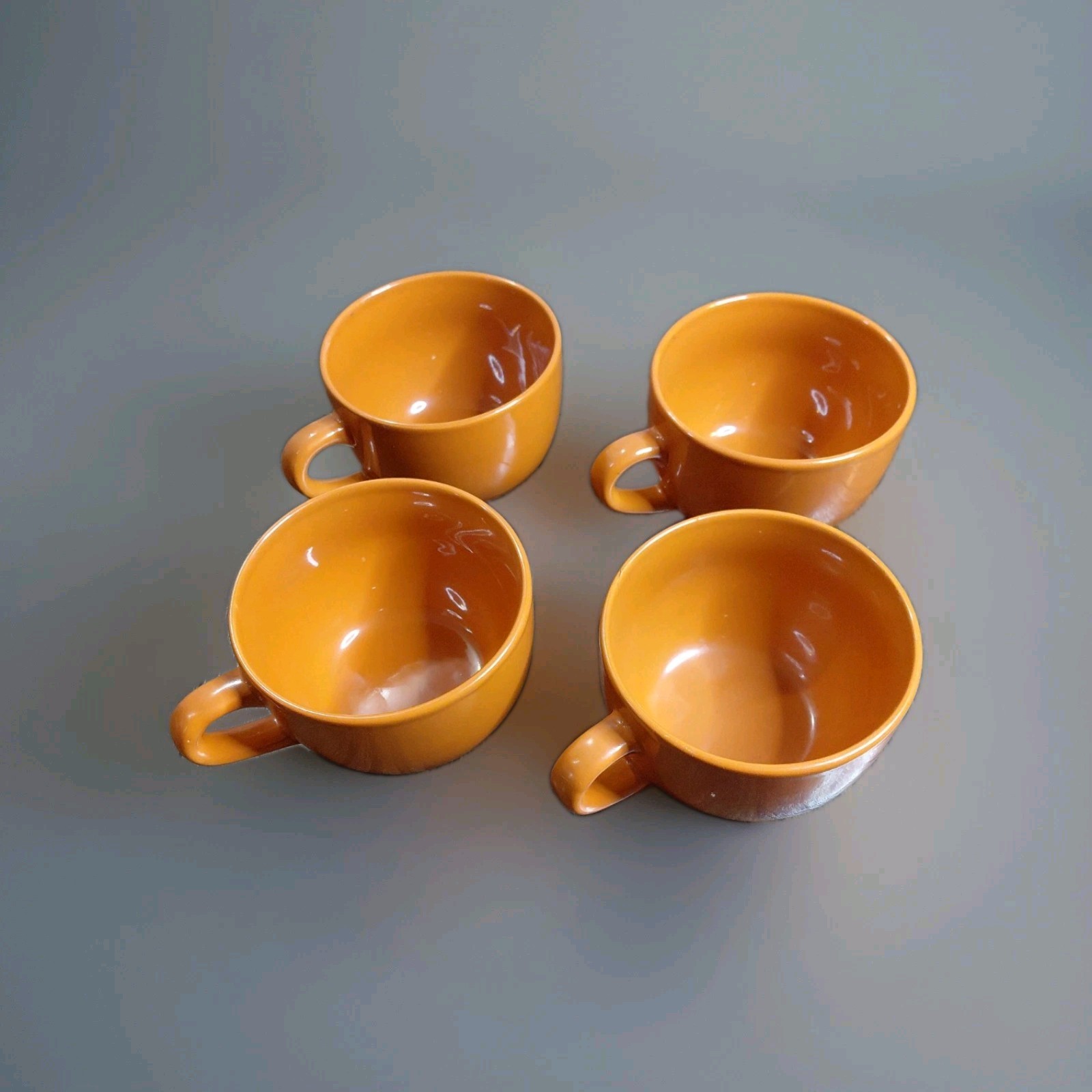 four vibrant orange ceramic jumbo mugs
