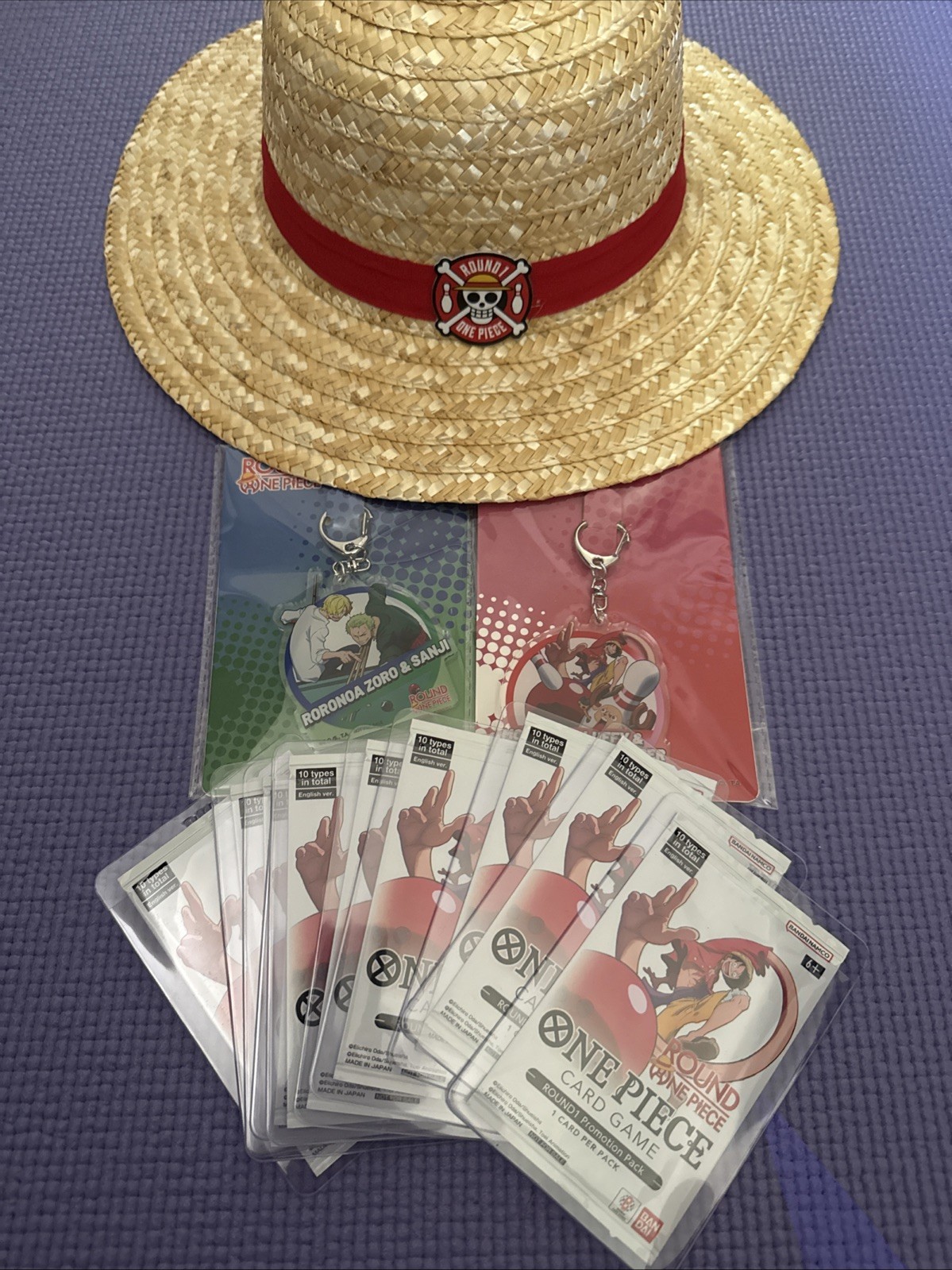Round1 One Piece TCG Promo Bundle 10 Sealed Packs, Straw Hat, 2 Keychains