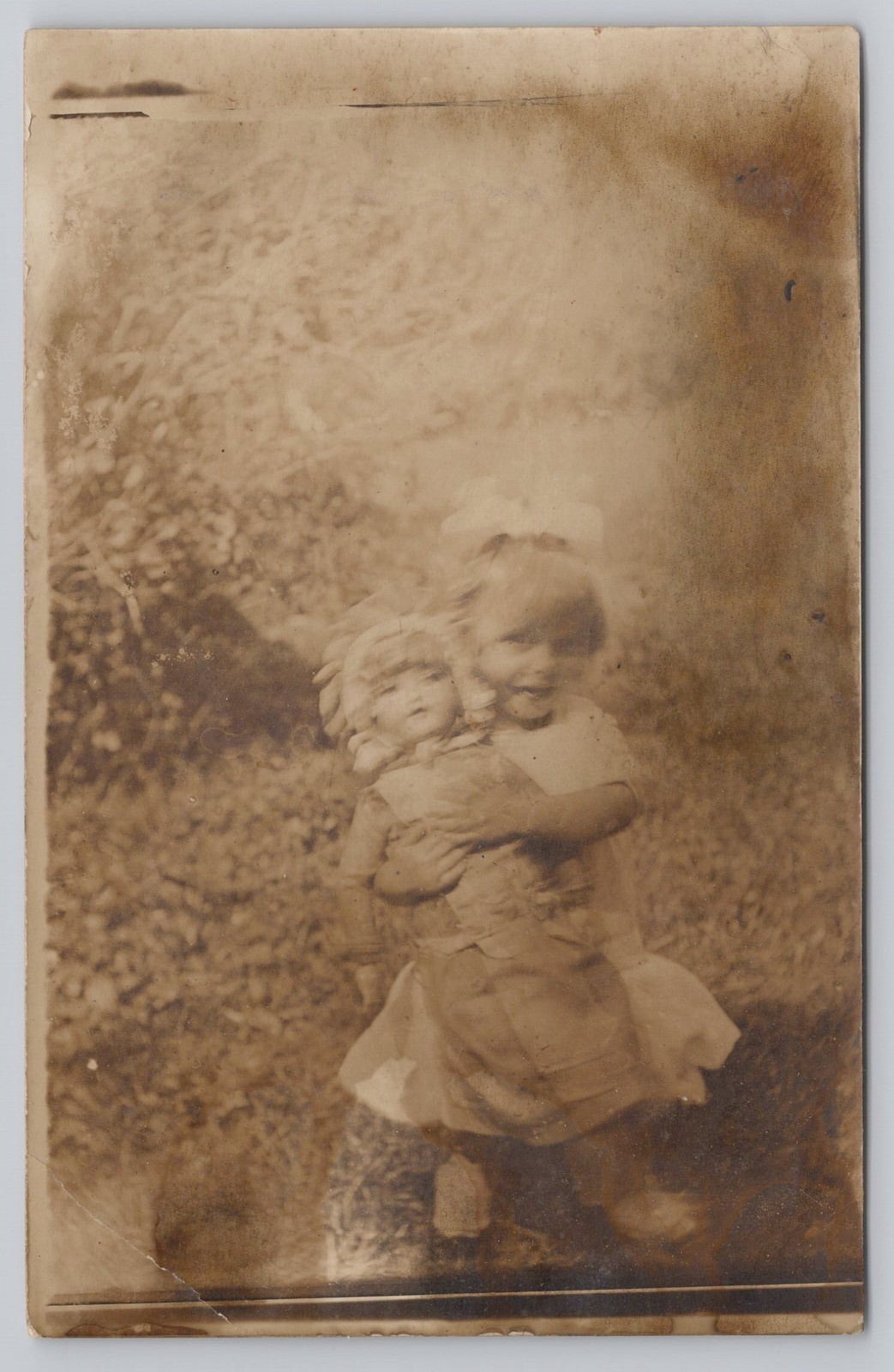 RPPC Happy Little Girl with Big Dollies Blurry Real Photo Vintage Postcard