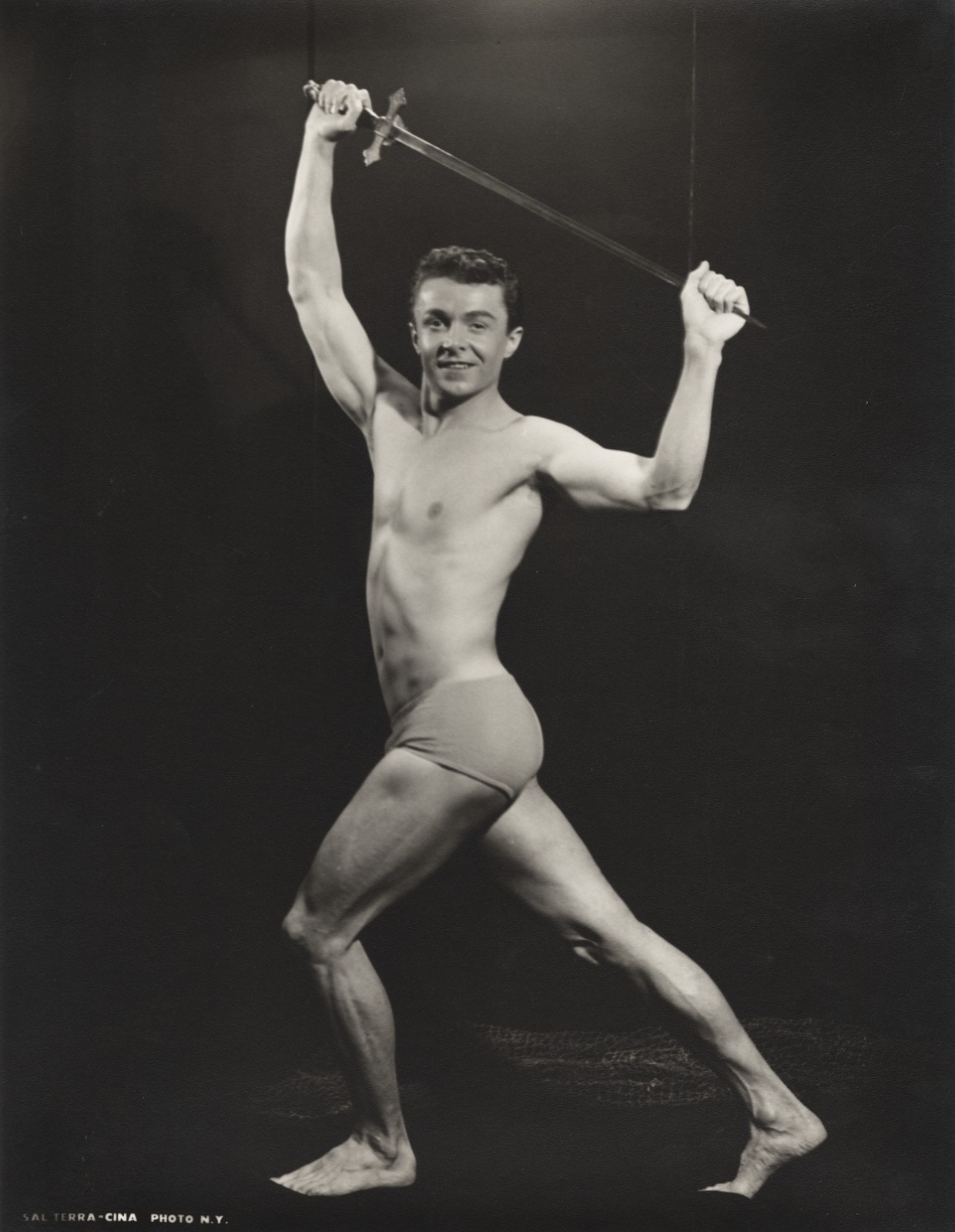 c. 1950's Bodybuilder Holding Sword Overhead Large Photograph by SAL TERRACINA c. 1950's Bodybuilder Holding Sword Overhead Large Photograph by SAL TERRACINA