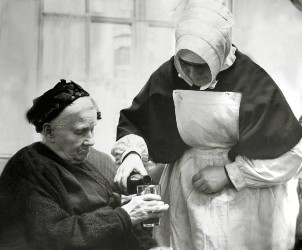 Nun pouring a drink for an elderly woman Historic Old Photo