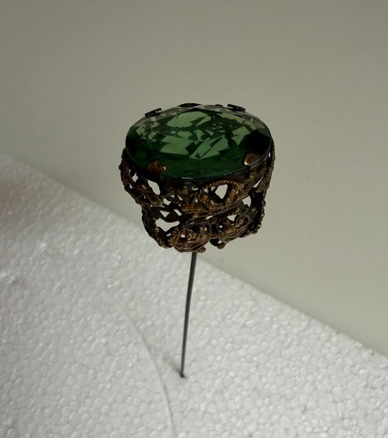 antique hat pin with large green cut glass and lots of filigree