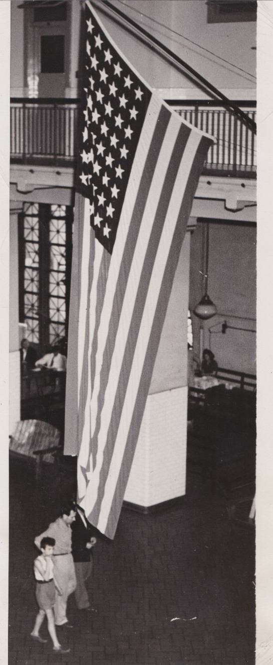 1947 Press Photo Immigrant Detainees pass Huge American Flag at Ellis Island
