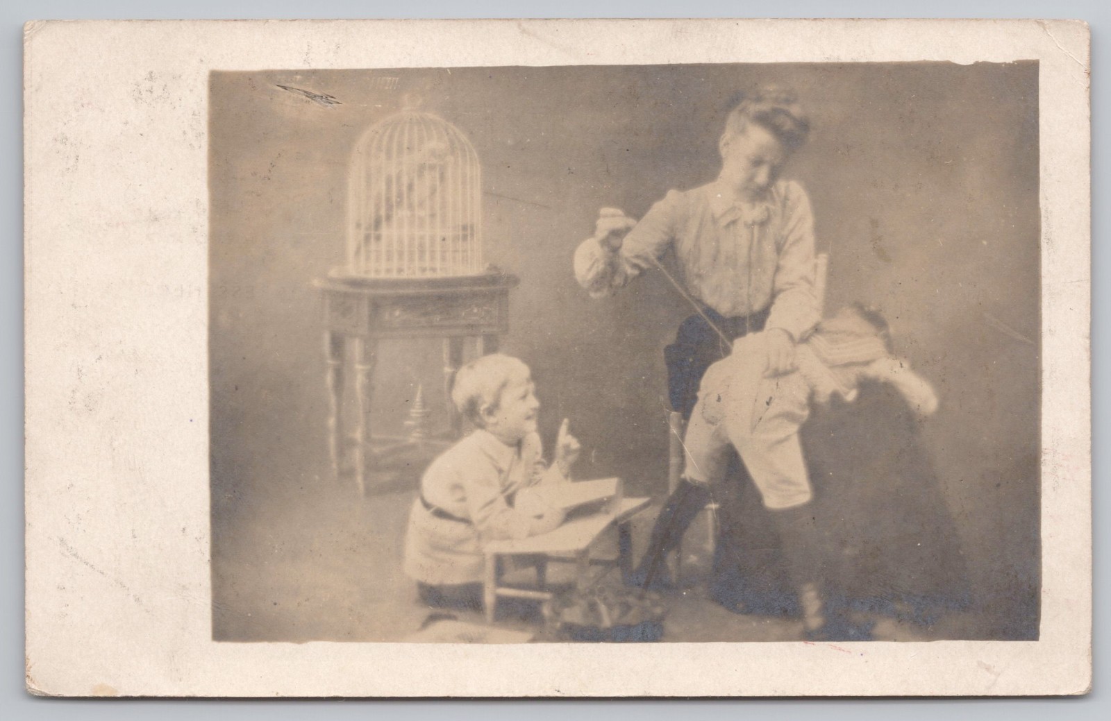 RPPC Posted 1909 Funny Studio Photo Postcard Woman Sewing Child\'s Pants Birdcage