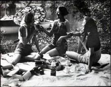 Three young women enjoy feeding each other bananas at a picnic - 1937 Old Photo picture