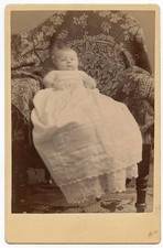 Original Cabinet Photo - Young Baby Propped in Chair Wearing Long Gown picture