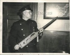 Press Photo Patrolman Gerald F. Bowen examining the machine gun found at school picture