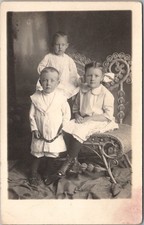 c1910s Studio Photo RPPC Postcard Two Boys & a Girl / Siblings / Wicker Chair picture