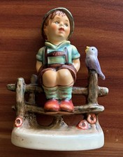 Bavarian boy sitting on a rustic fence next to a bird figurine 